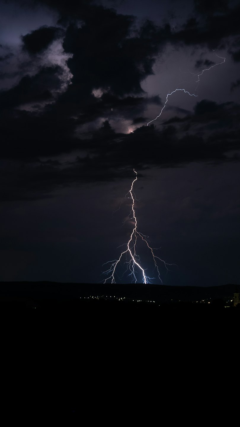 A bright lightning bolt strikes toward the dark horizon.