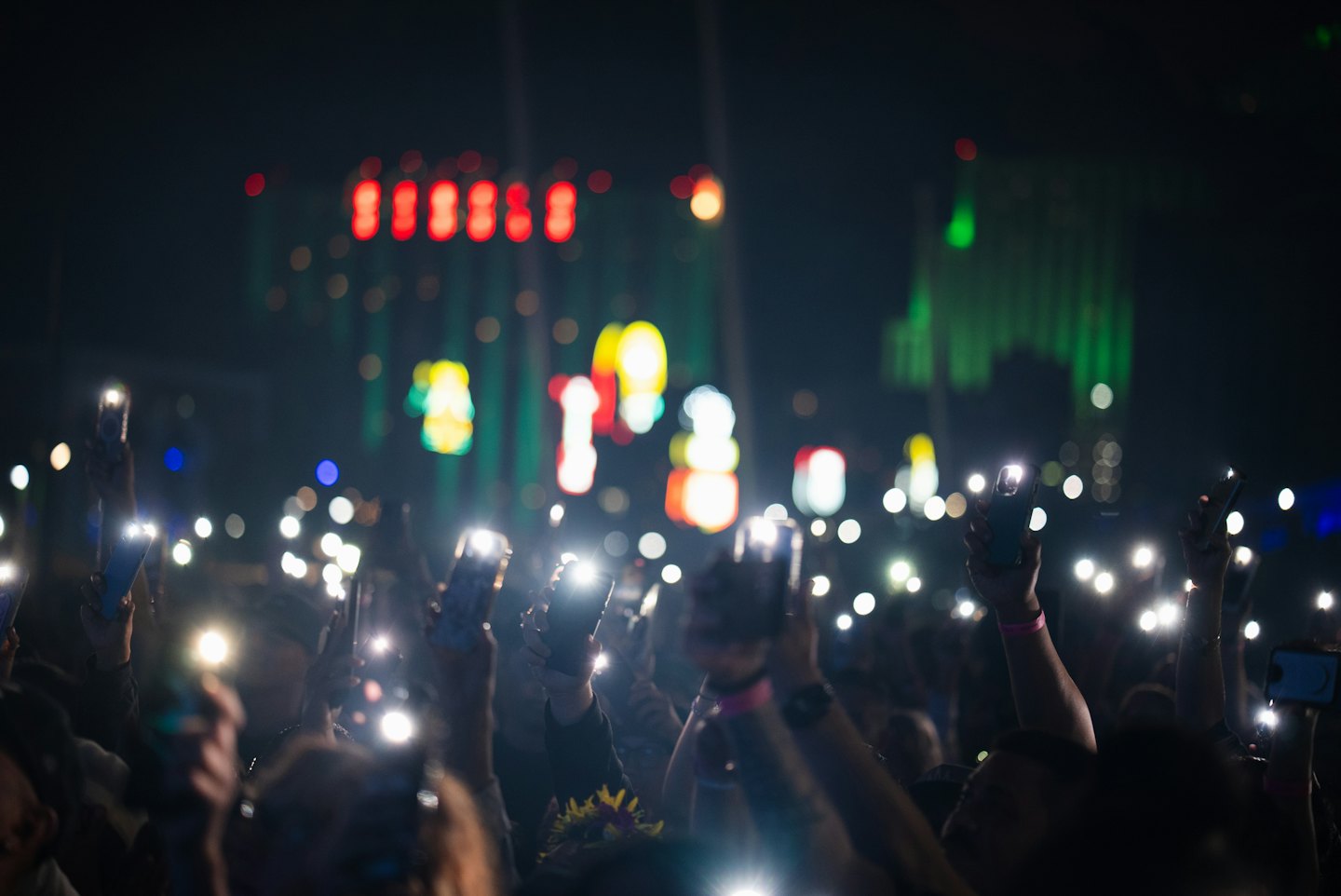 Concert audience holds up glowing smartphones during a live show.