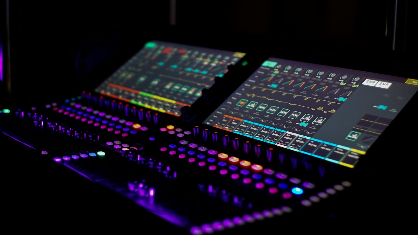 Professional sound mixing console with illuminated buttons and digital waveforms.